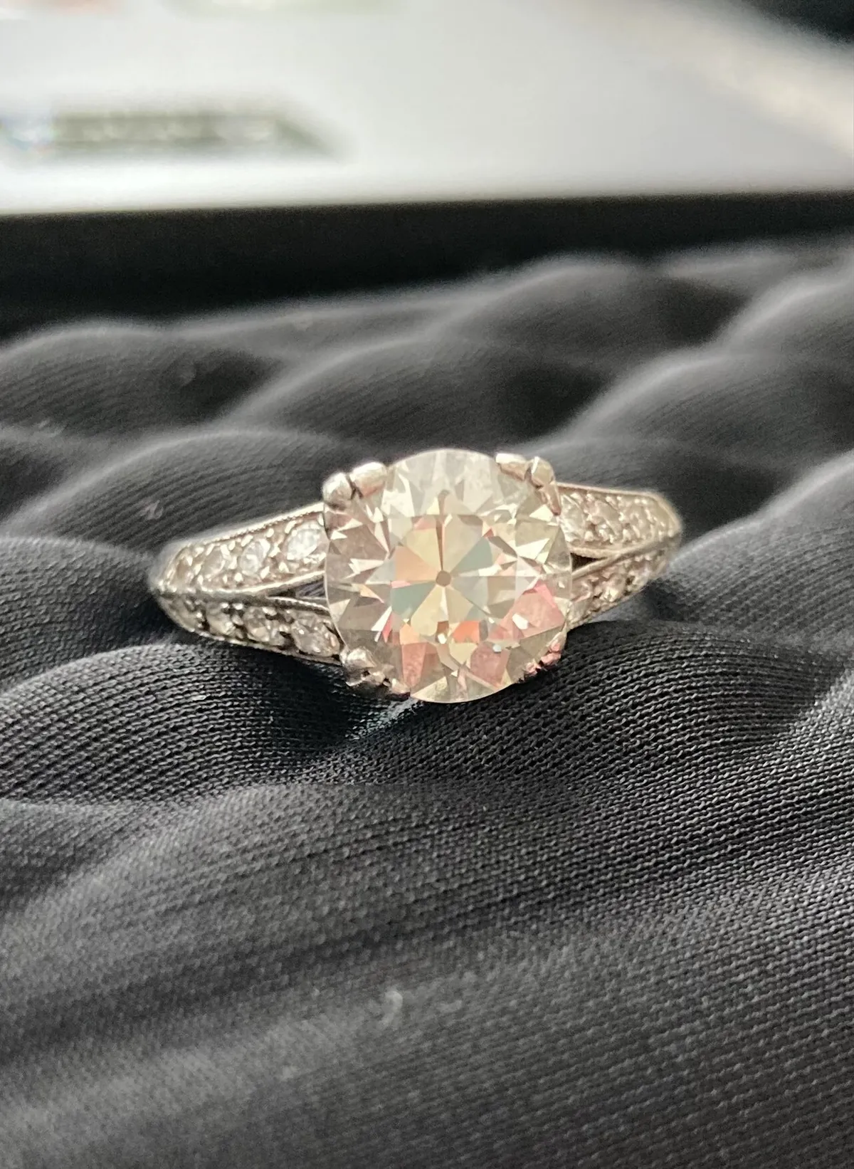 Platinum ring set with a large old European cut diamond on dark fabric