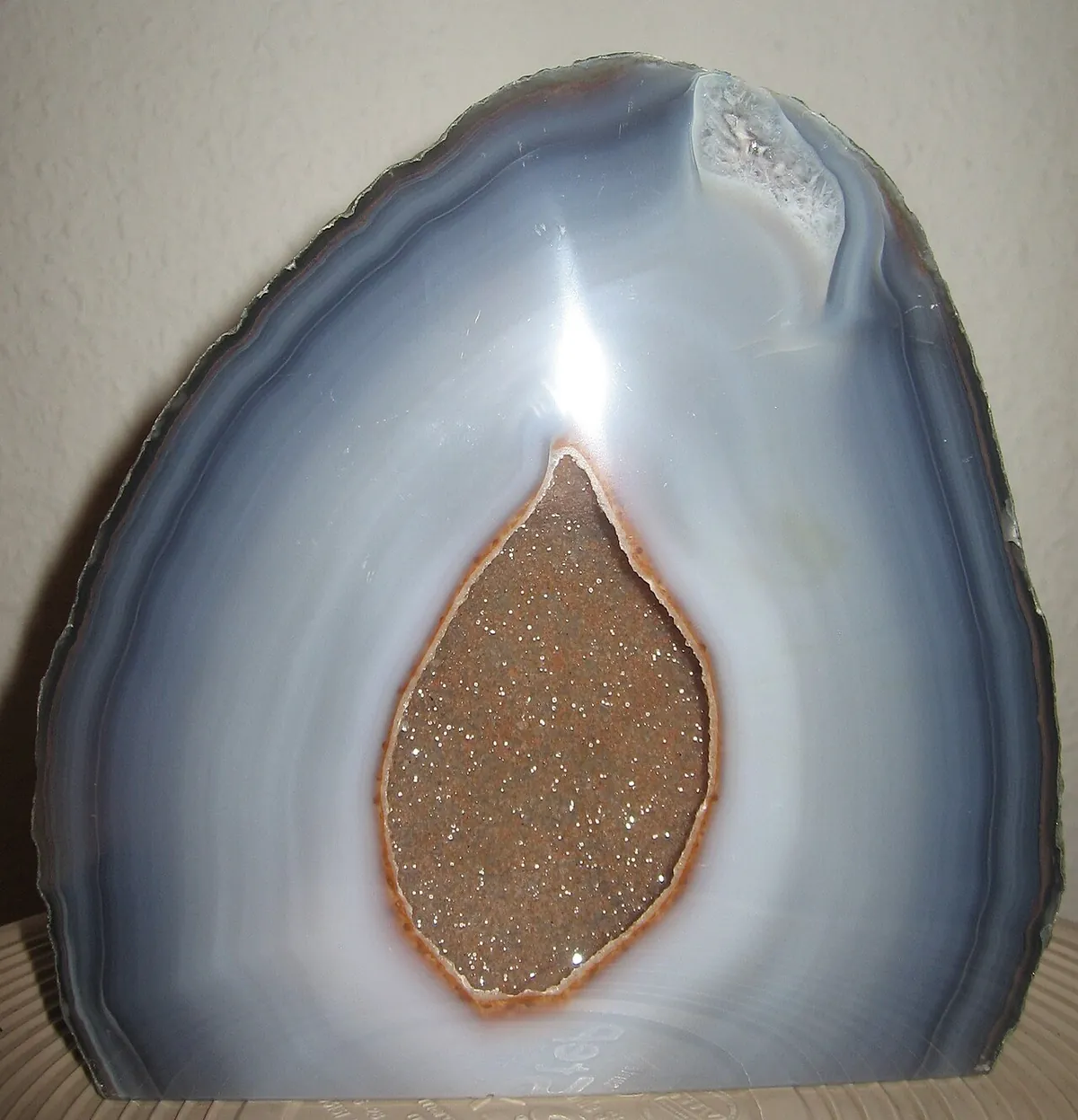 Polished gray banded agate with a cavity lined in tiny sparkling quartz crystals