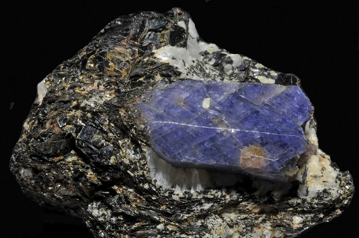 Rough blue sapphire crystal embedded in dark mica rock