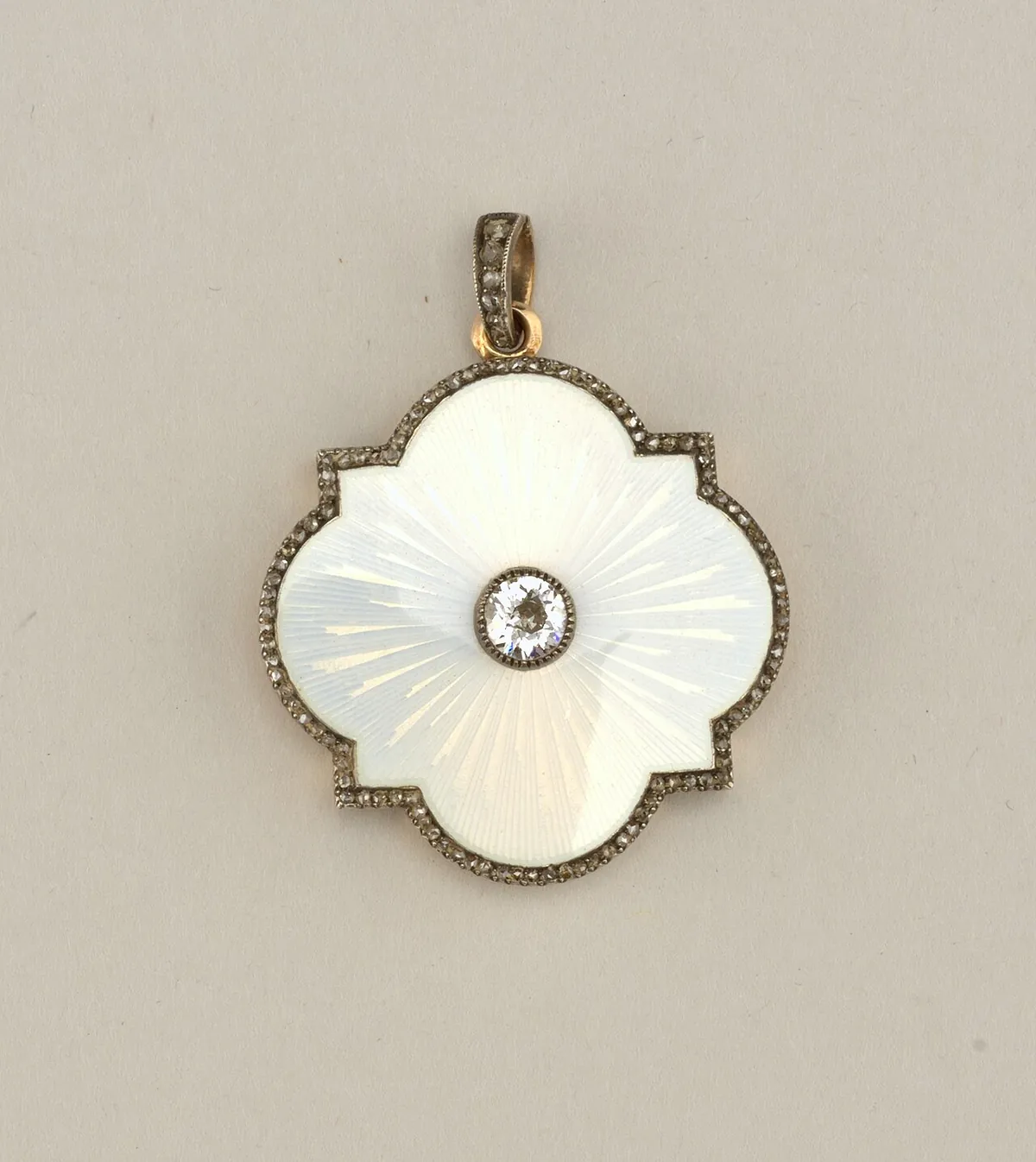 White enamel quatrefoil locket centered with a round old mine cut diamond